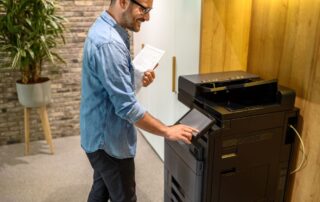 Casual business man interacts with a color mfp in an office setting.